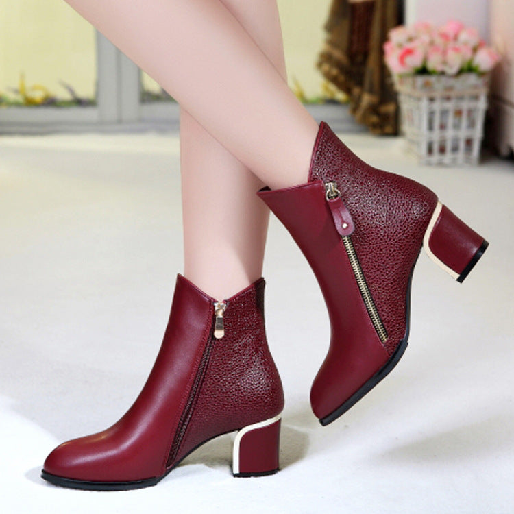 Red high-heeled ankle boots with zippers worn by a person on a light background