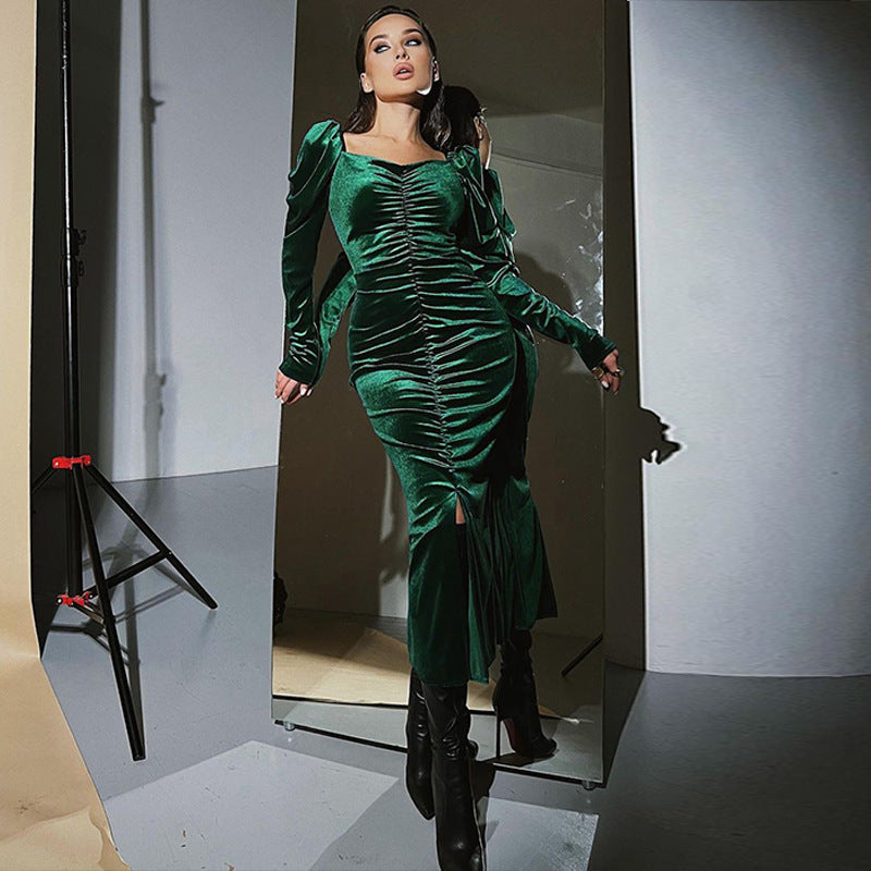 Woman in a green velvet dress standing in a photo studio.