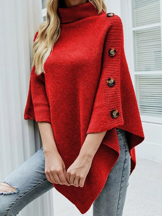 Red poncho with button details worn by a person, against a neutral background