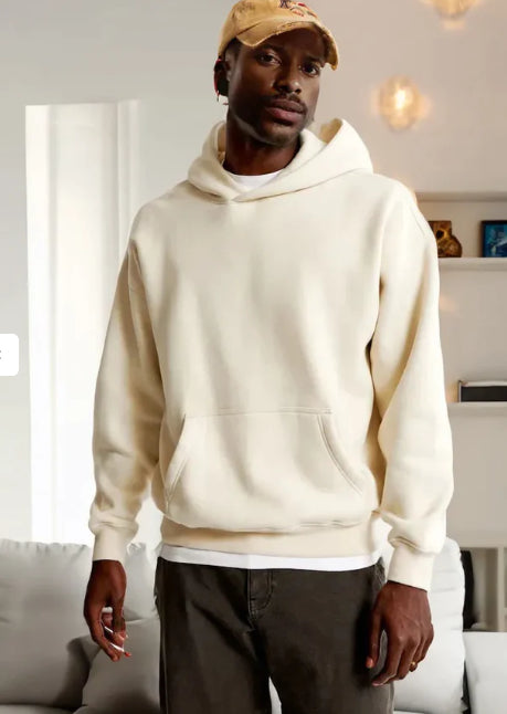 Man wearing a cream hoodie and beige cap indoors