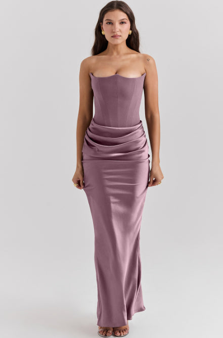 Woman wearing a strapless, floor-length mauve dress on a light gray background