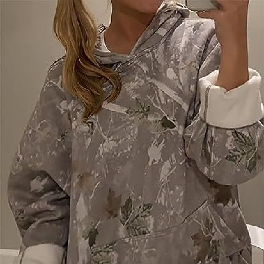 Person wearing a camouflage hoodie with white cuffs and collar.