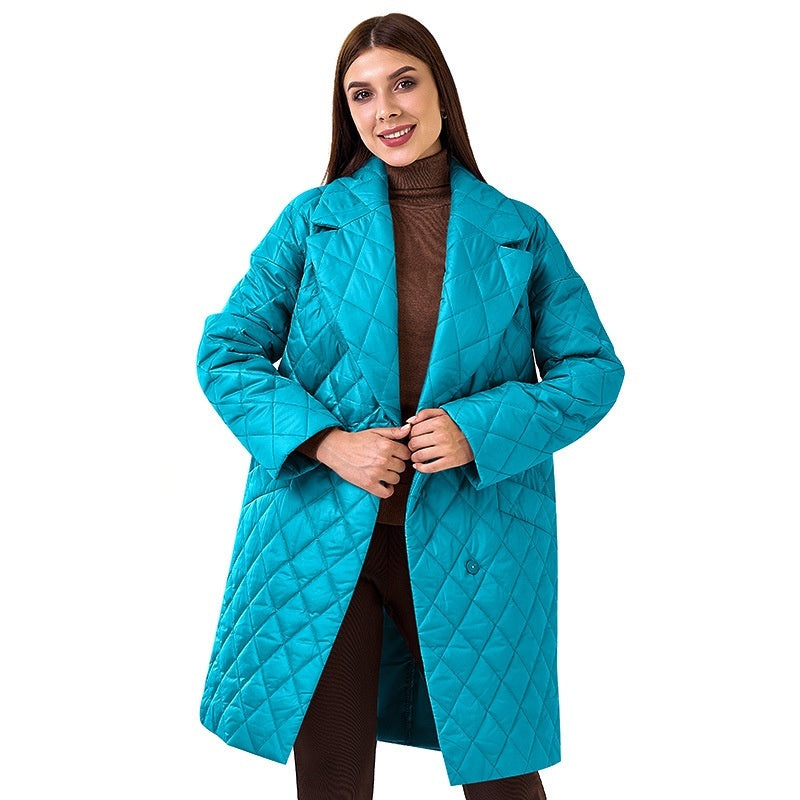 Woman wearing a turquoise quilted coat on a white background