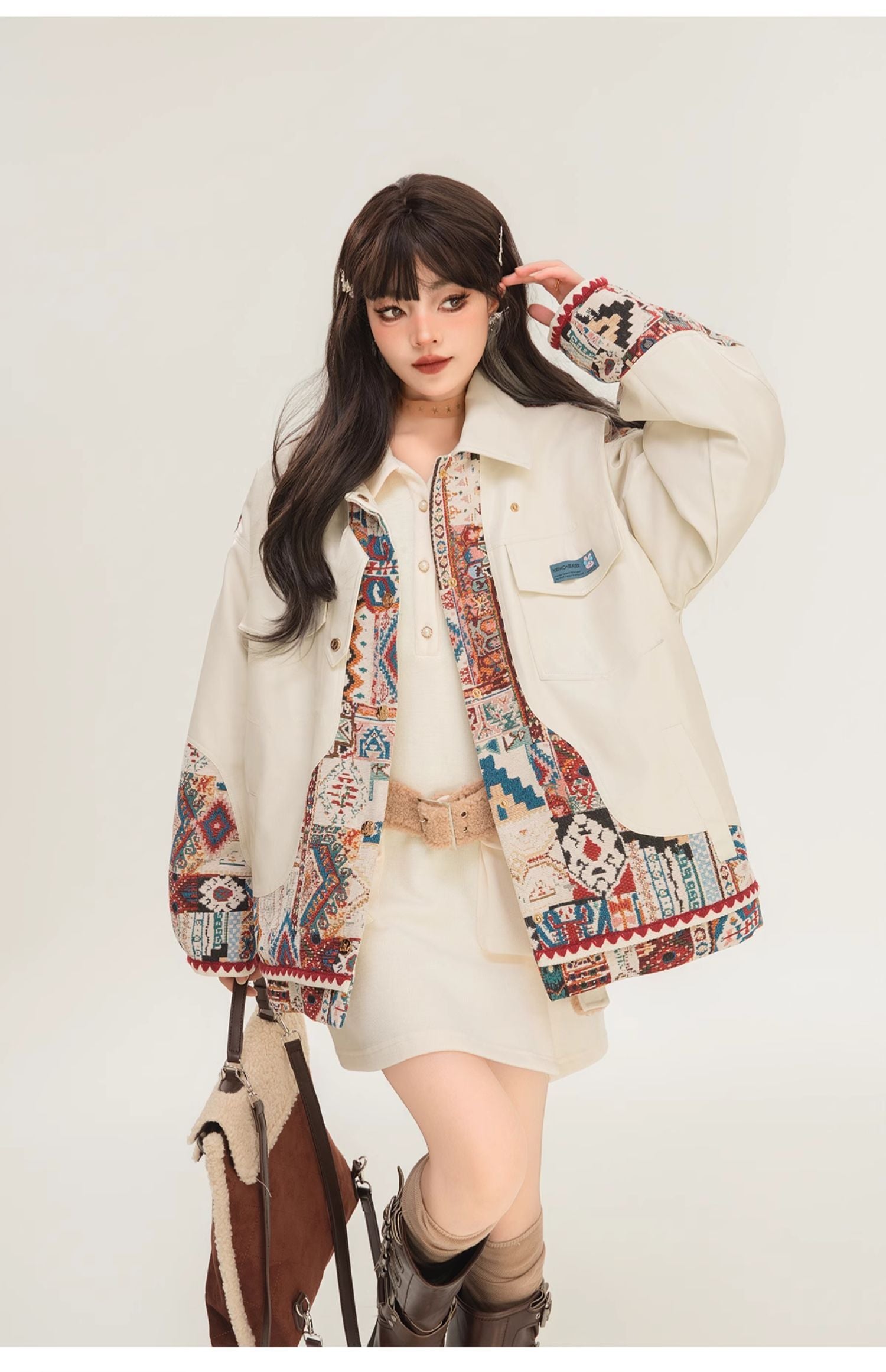 Person wearing a patterned jacket over a white outfit with a white background