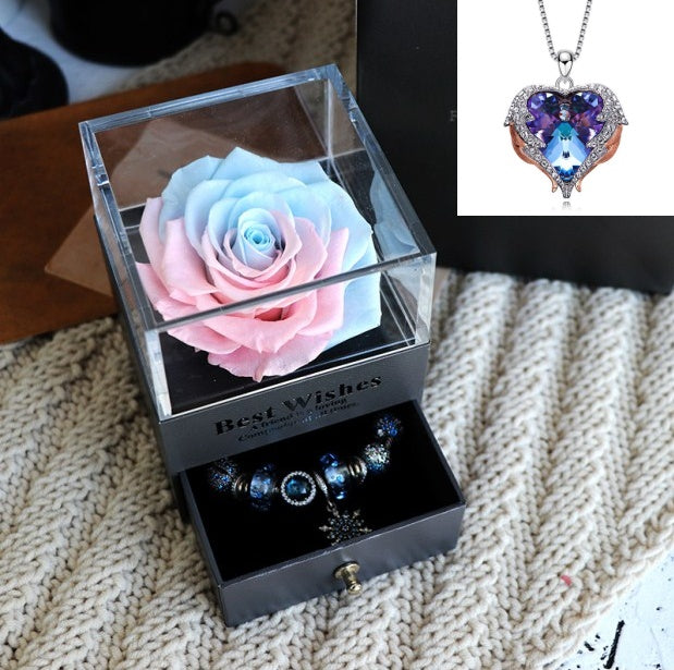 Glass box with a preserved rose and jewelry set on a textured surface, with a heart-shaped pendant shown inset.