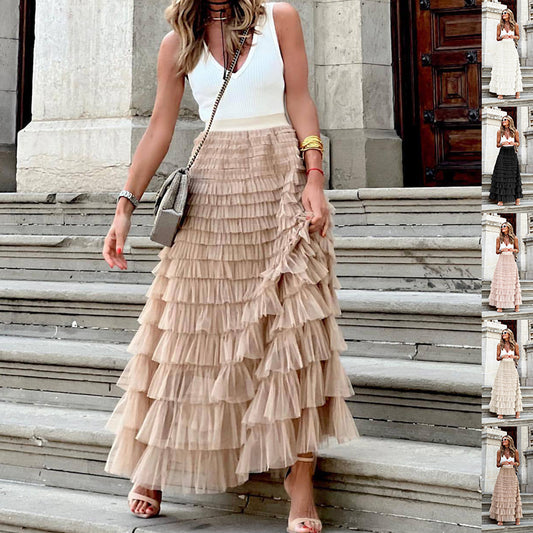 Woman wearing a white top and beige ruffled skirt standing on stone steps.