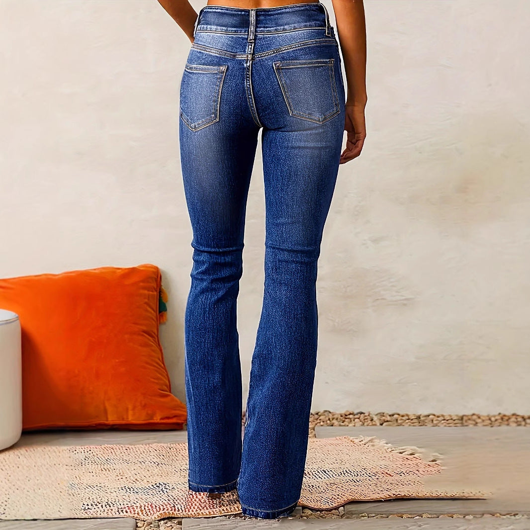 Person wearing blue jeans standing in a room with an orange pillow and textured wall.