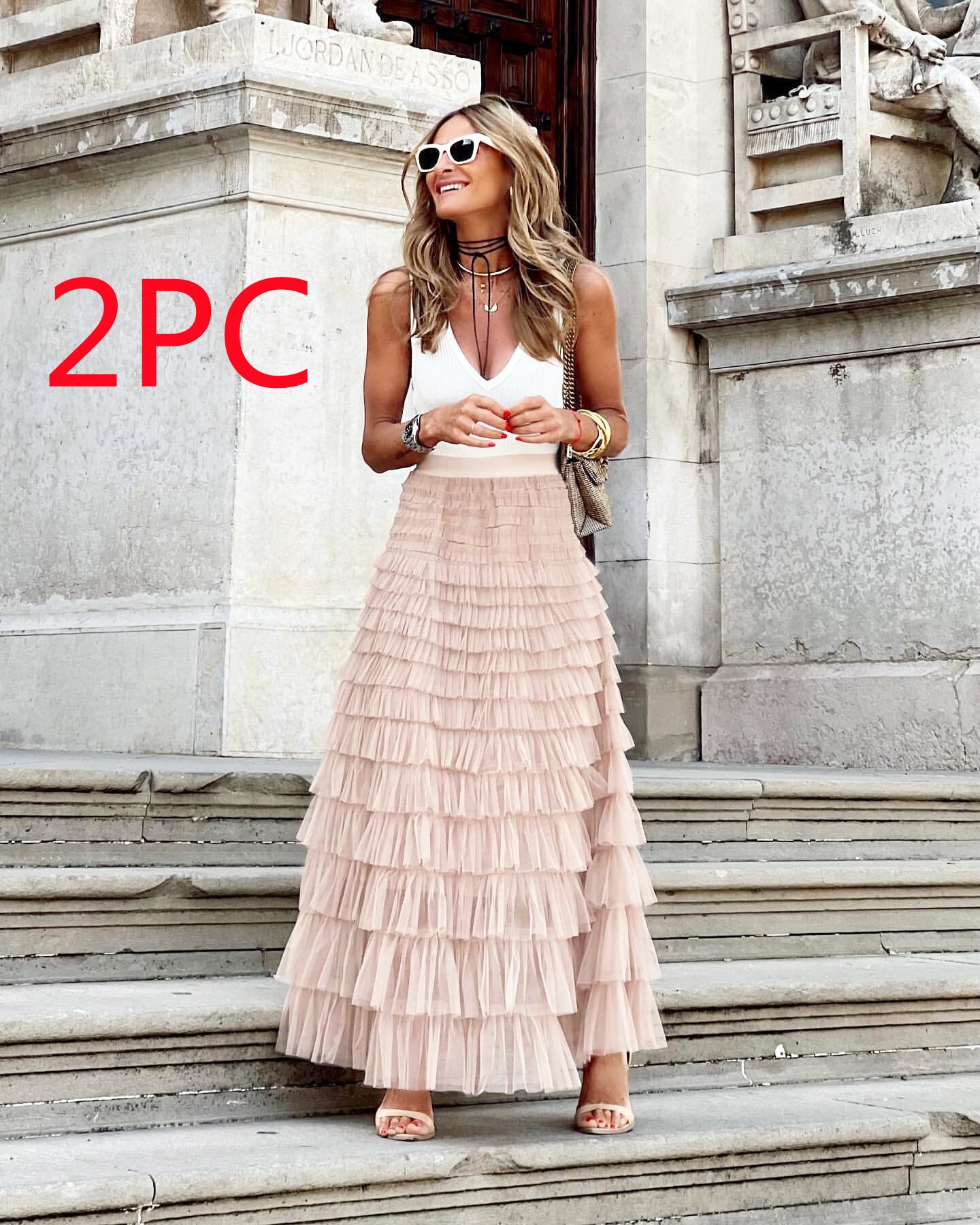 Woman in a white top and layered pink skirt standing on stone steps with '2PC' text.