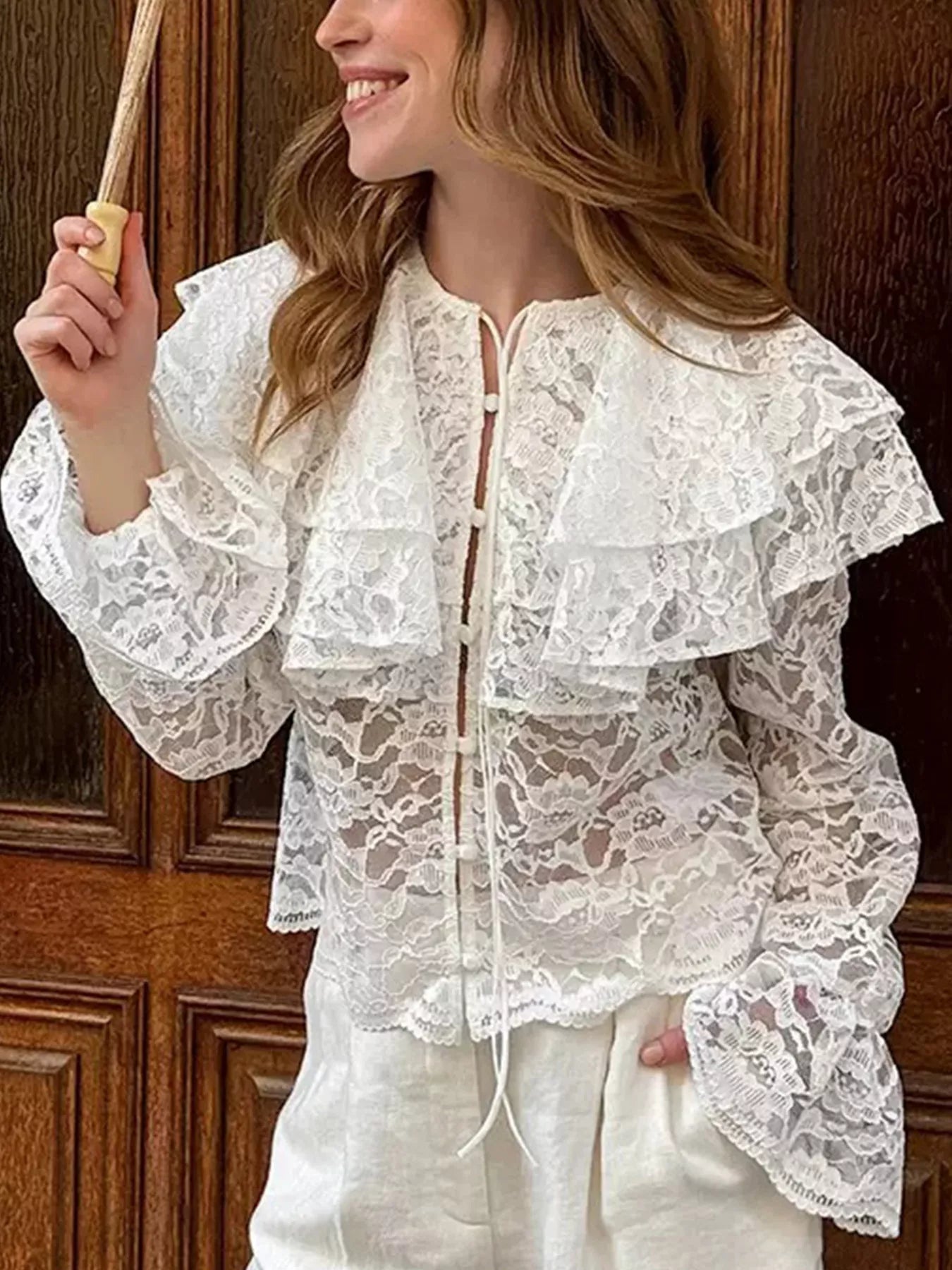 Woman wearing a white lace blouse with a wooden door in the background
