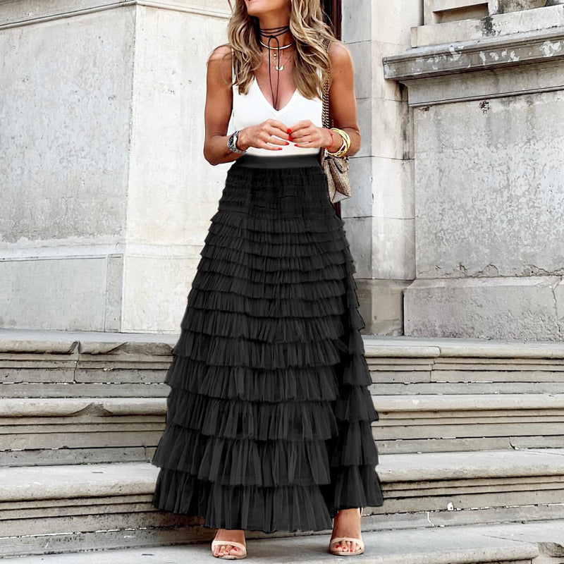 Woman wearing a white top and black tiered skirt standing on stone steps.