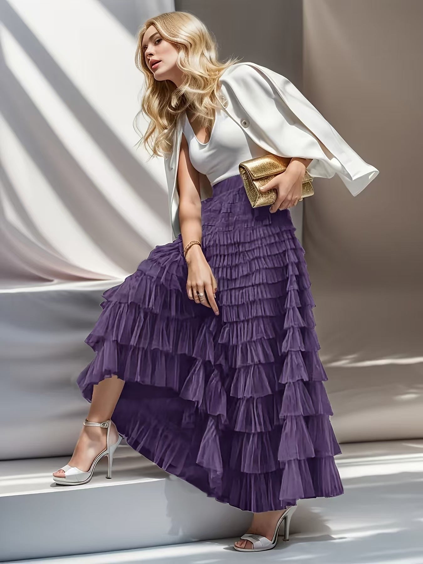 Woman wearing a white top and purple ruffled skirt with a gold clutch against a neutral background