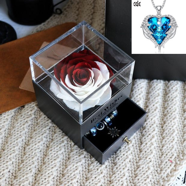 Glass box with preserved roses and jewelry on a textured surface