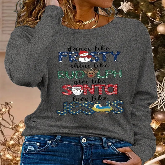 Gray sweatshirt with Christmas-themed text in front of a decorated Christmas tree.