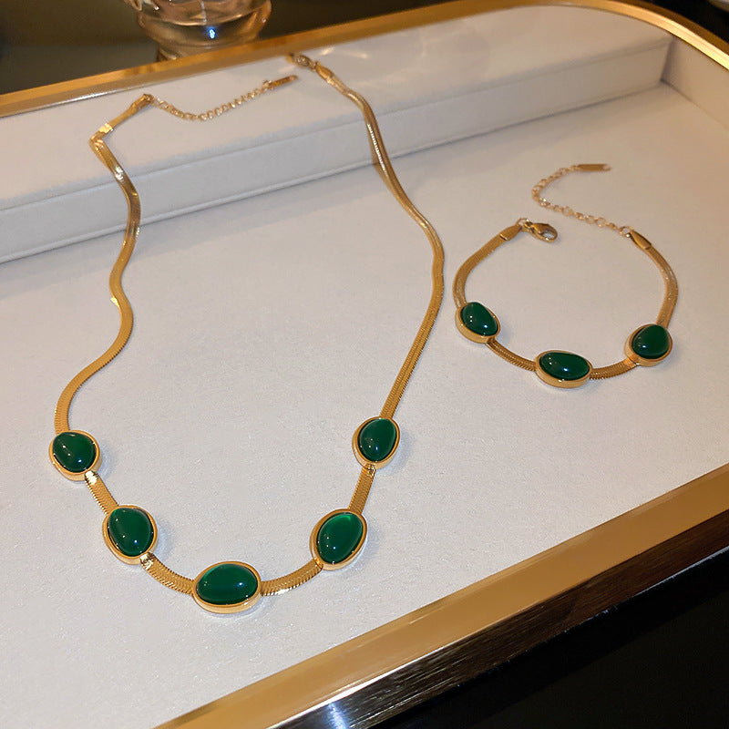 Gold necklace with green stones on a white tray