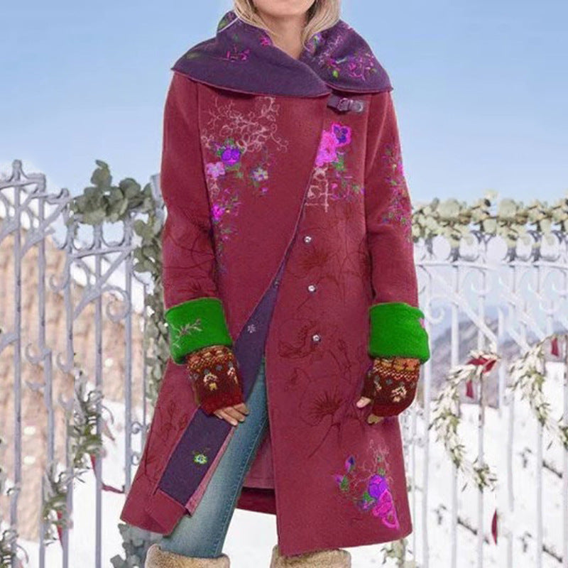 Person wearing a colorful embroidered coat with a floral design against a decorative metal gate.