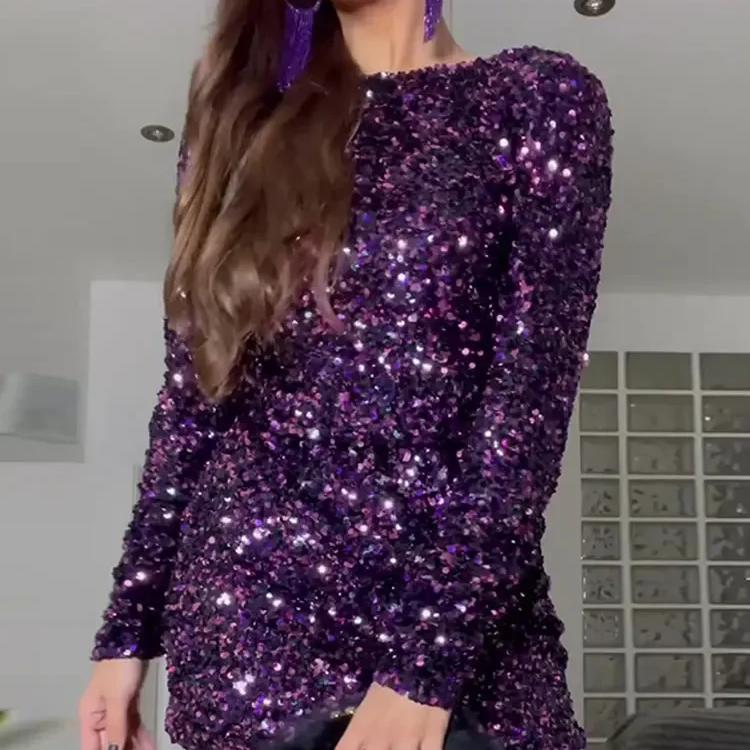 Person wearing a sparkling purple dress with long sleeves indoors.