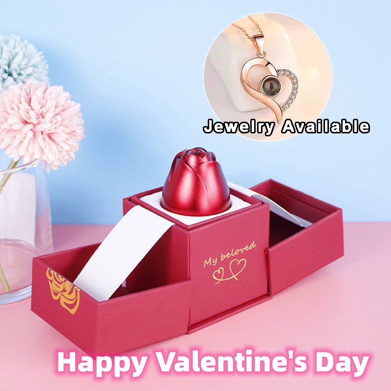 Red jewelry box with a heart design on a pink surface, featuring a small red heart-shaped object inside.