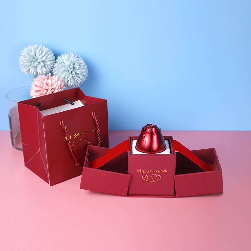 Red jewelry box with 'My beloved' text on a pink surface and blue background