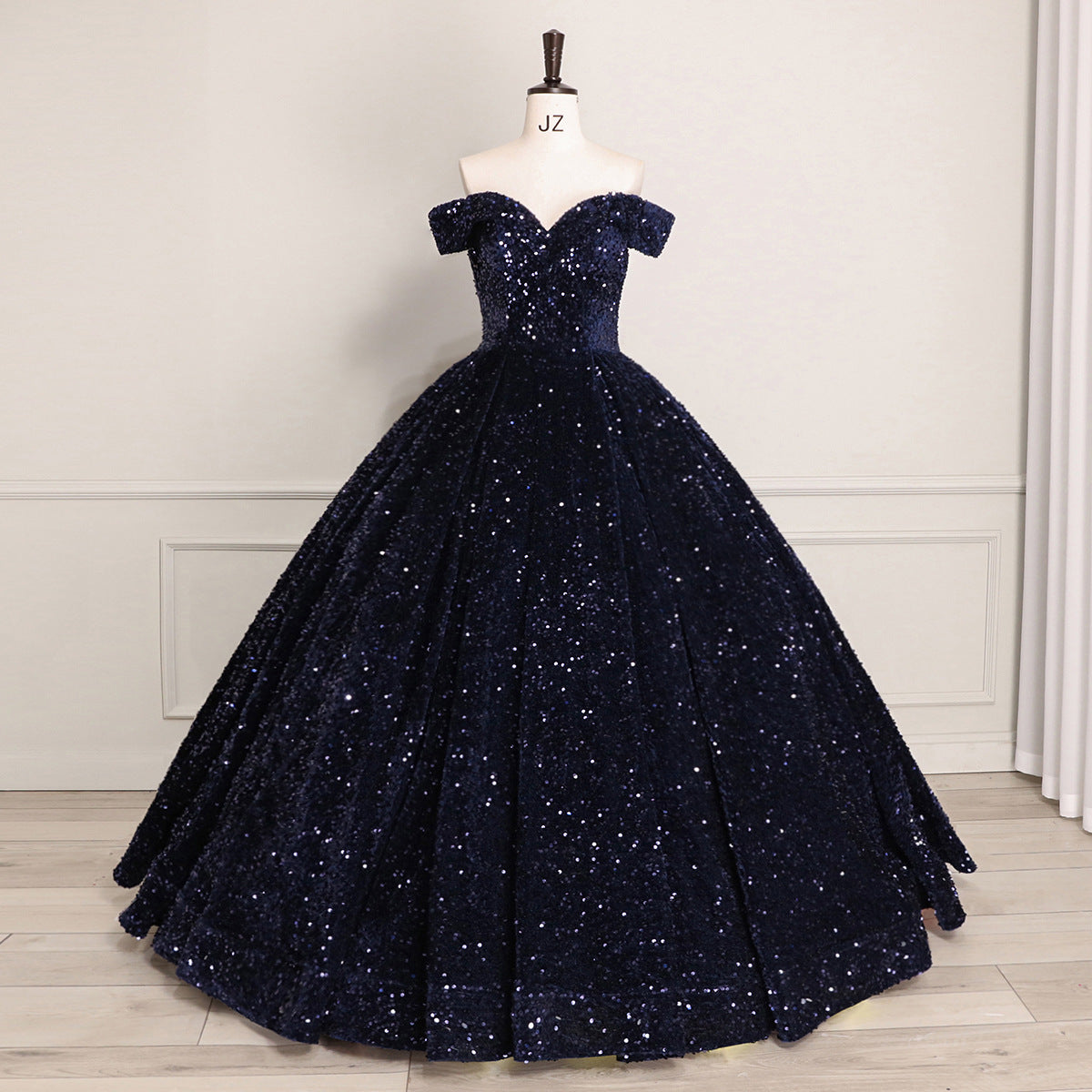 Navy blue sequin ball gown on a mannequin against a neutral background