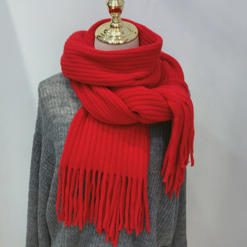 Red scarf with fringe draped over a gray garment on a white background