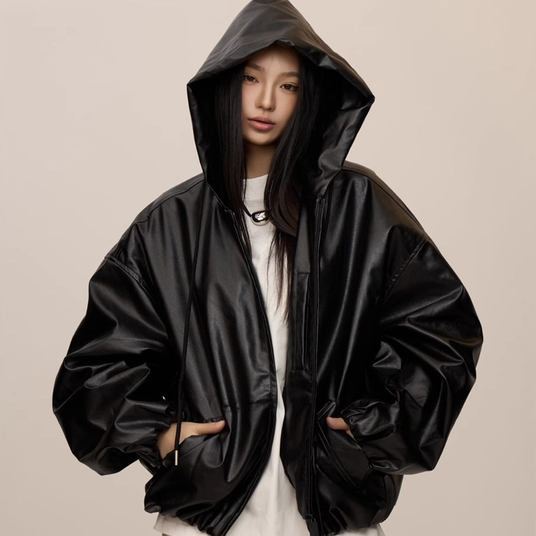 Person wearing a black raincoat on a beige background