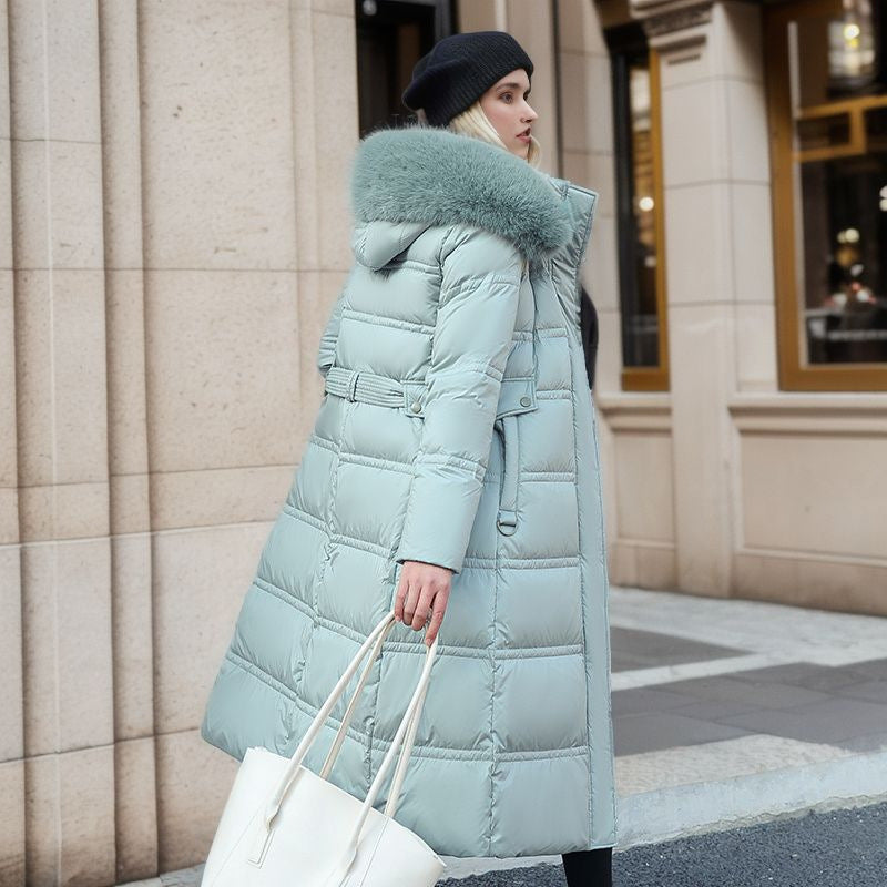 Woman wearing a long light blue puffer coat with a fur-lined hood in an urban setting.