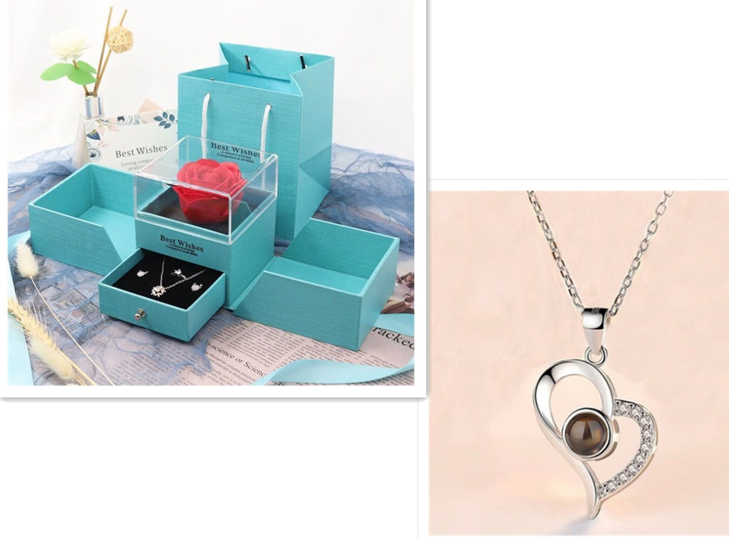 Teal jewelry organizer with a rose and earrings, and a silver heart-shaped necklace with a brown stone on a beige background.