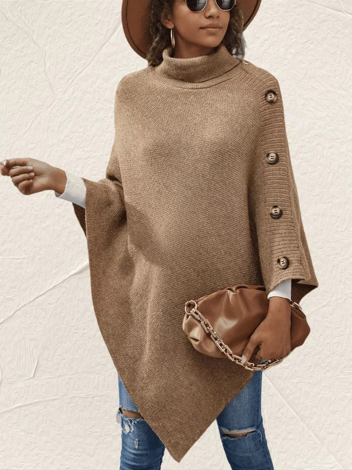 Woman wearing a brown poncho with buttons, holding a matching handbag against a light background