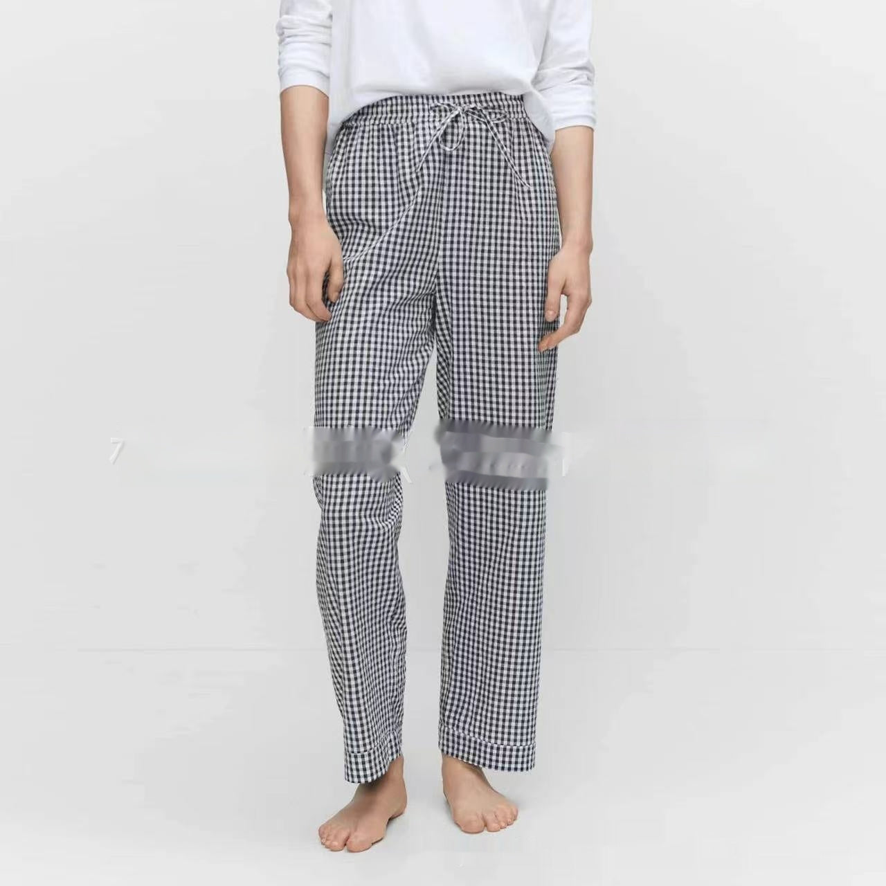 Person wearing black and white checkered pants with sheer panels on a white background