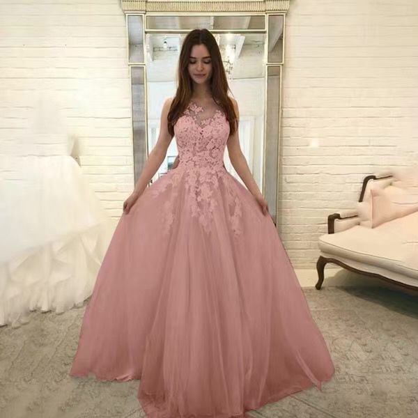 Woman wearing a pink evening gown in a room with white walls and furniture.