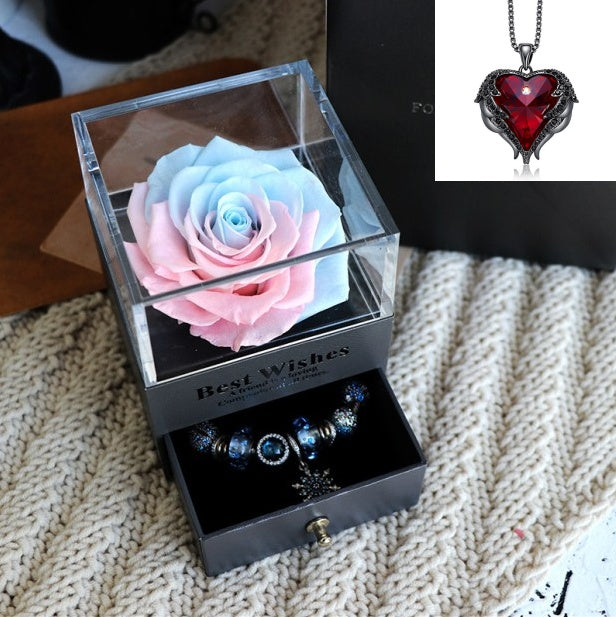 Glass box with a preserved rose and jewelry, heart-shaped pendant in the corner.