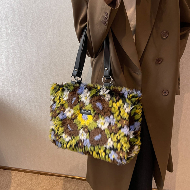 Fluffy multicolored handbag held by a person wearing a brown coat.