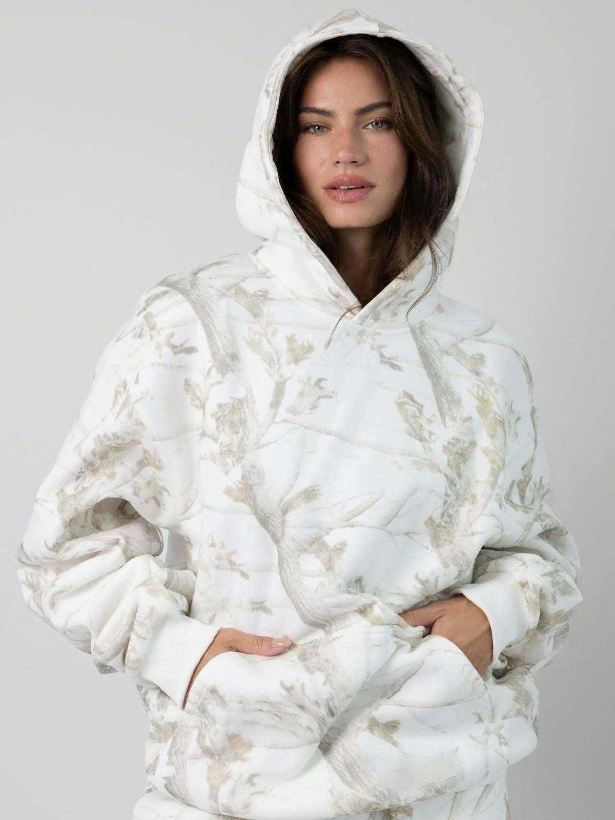 Person wearing a white floral-patterned hoodie on a gray background