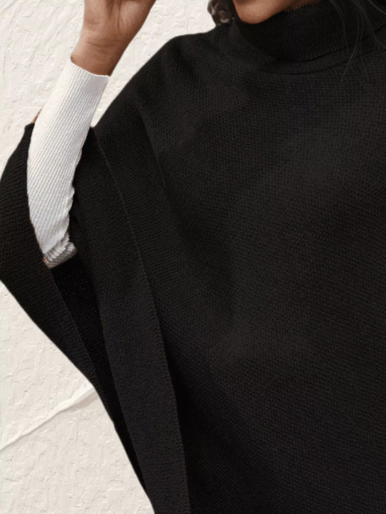 Person wearing a black outfit with a white sleeve in a close-up shot.