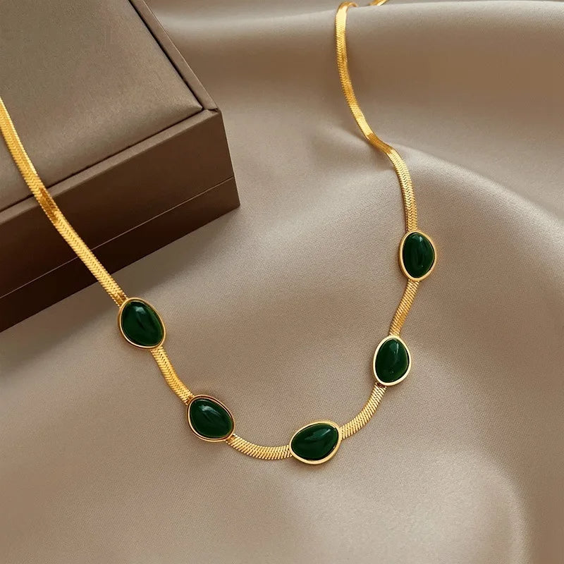 Gold necklace with green stones on a beige fabric background