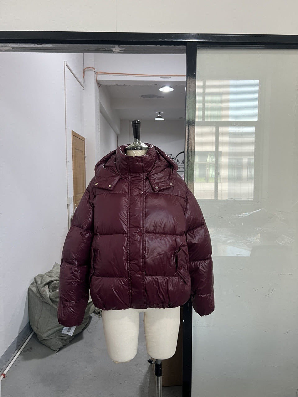 Maroon puffer jacket on a mannequin against a white wall.