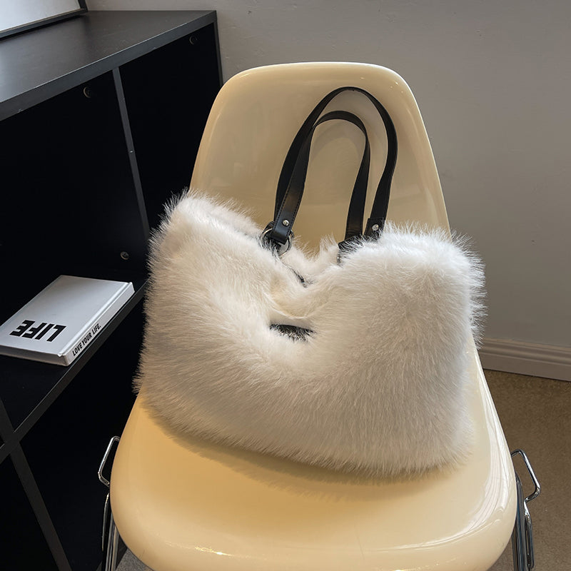 White fluffy handbag on a beige chair with a black shelf and book in the background.