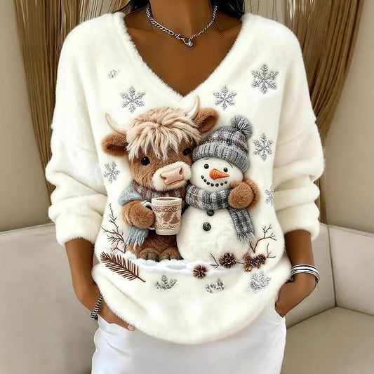 White sweater with a design of a cow, snowman, and snowflakes on a neutral background