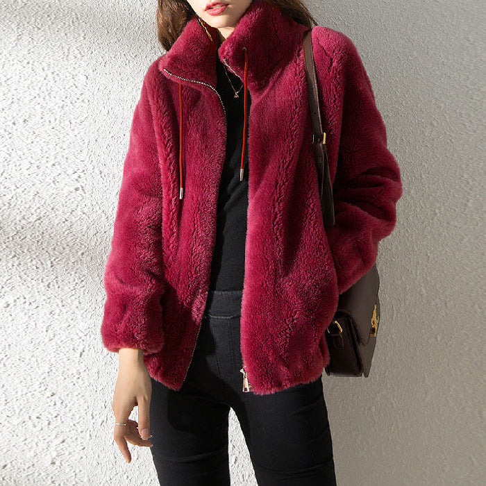 Person wearing a burgundy fur coat against a neutral background