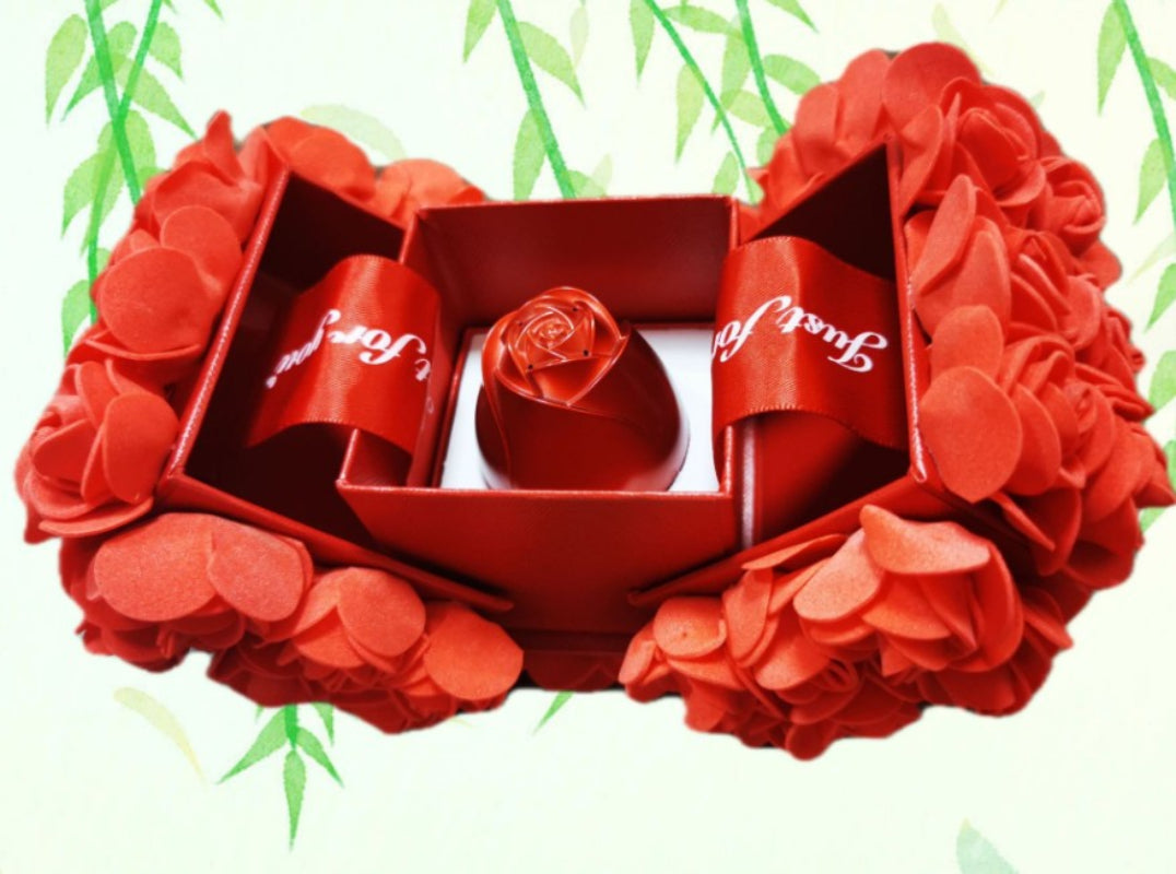 Red floral arrangement with a box and ribbons on a white background