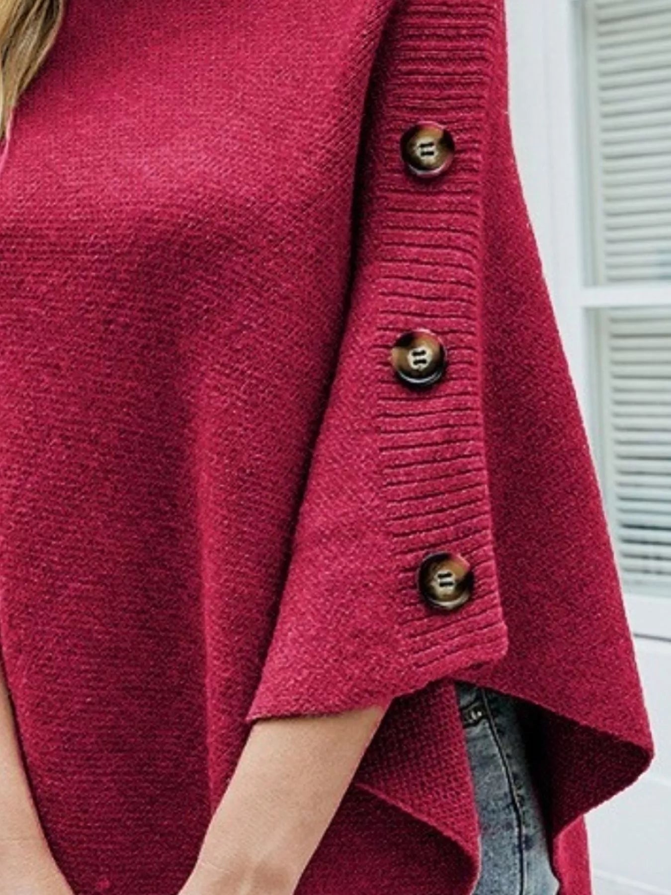 Close-up of a red cardigan with gold buttons on a blurred background