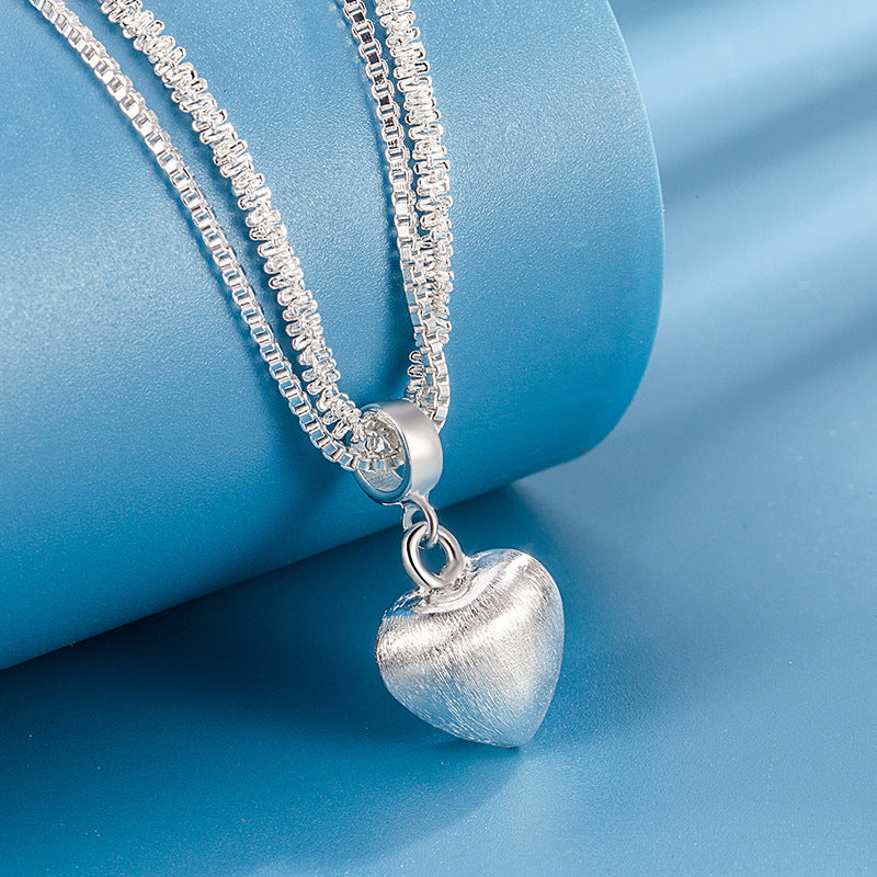 Silver heart-shaped pendant necklace on a blue background