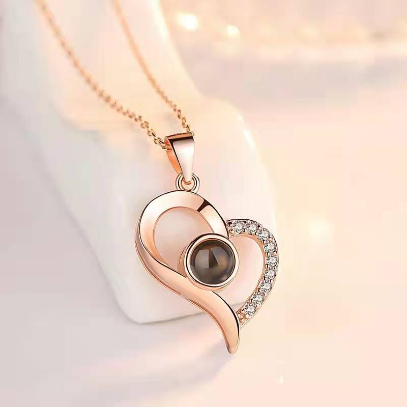 Rose gold heart-shaped pendant with central gemstone on a soft background