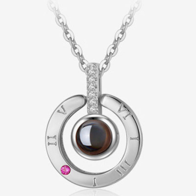 Silver necklace with a circular pendant featuring Roman numerals and gemstones on a white background