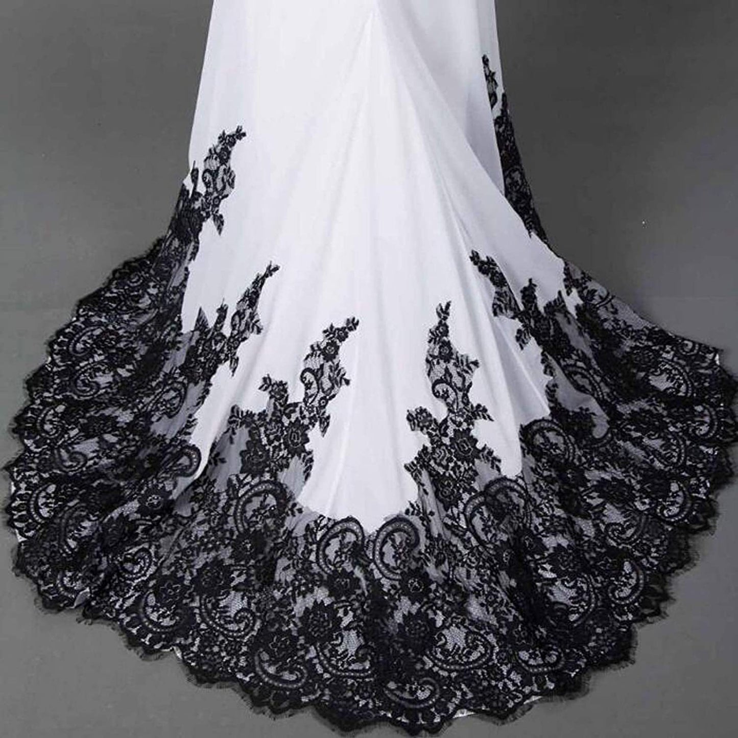 White fabric with black lace detailing on a gray background
