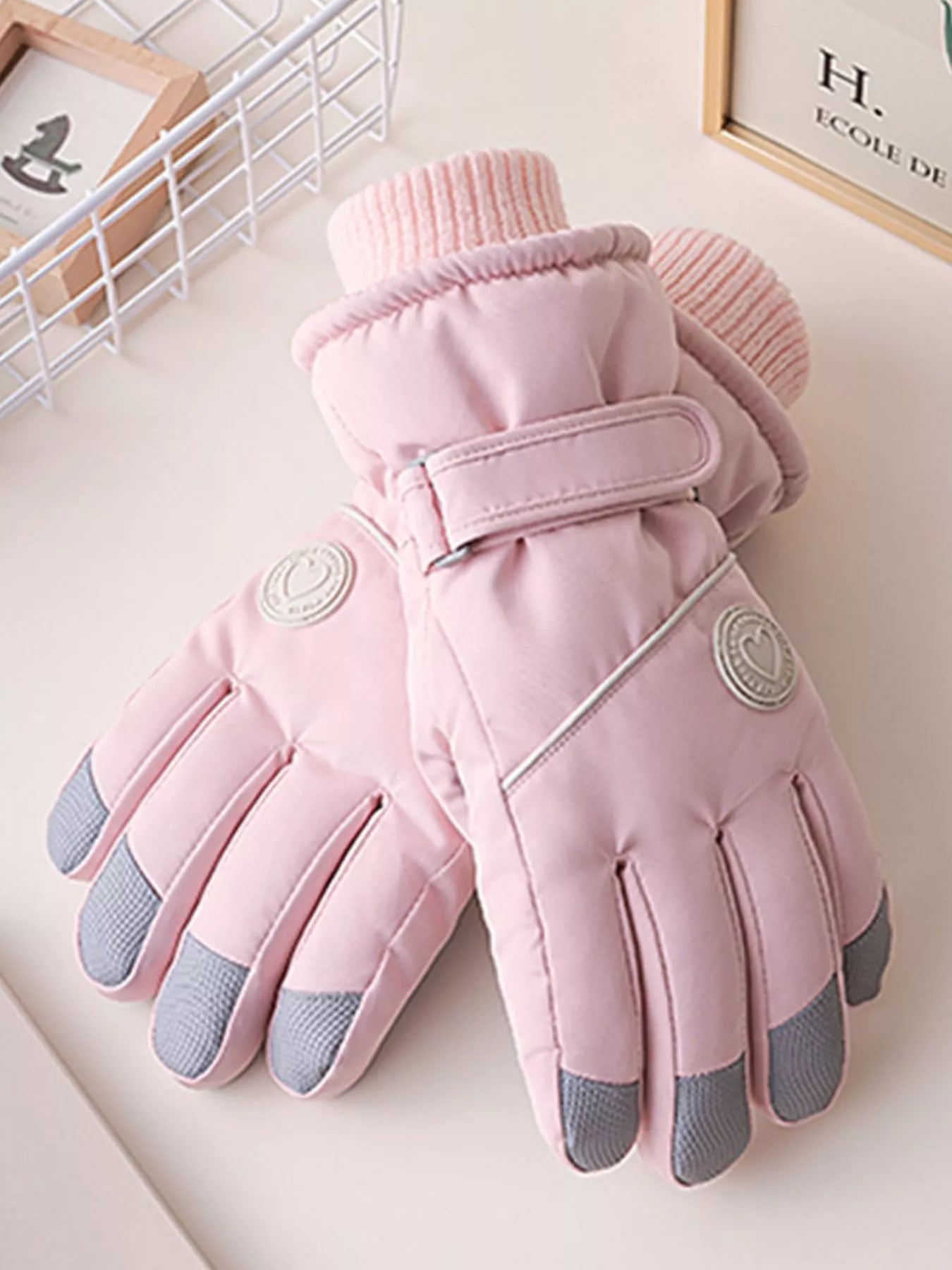 Pink gloves with gray touch tips on a white surface