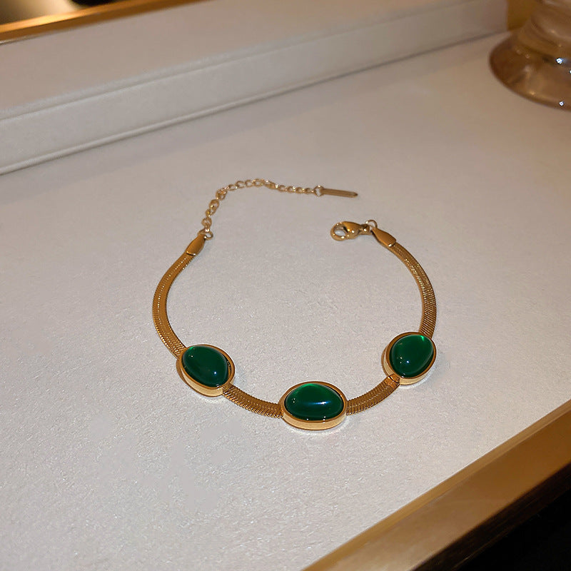 Gold necklace with green stones on a white surface