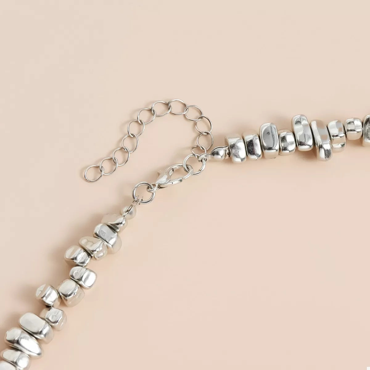 Silver beaded necklace on a beige background
