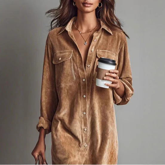 Woman wearing a brown corduroy dress holding a coffee cup against a gray background