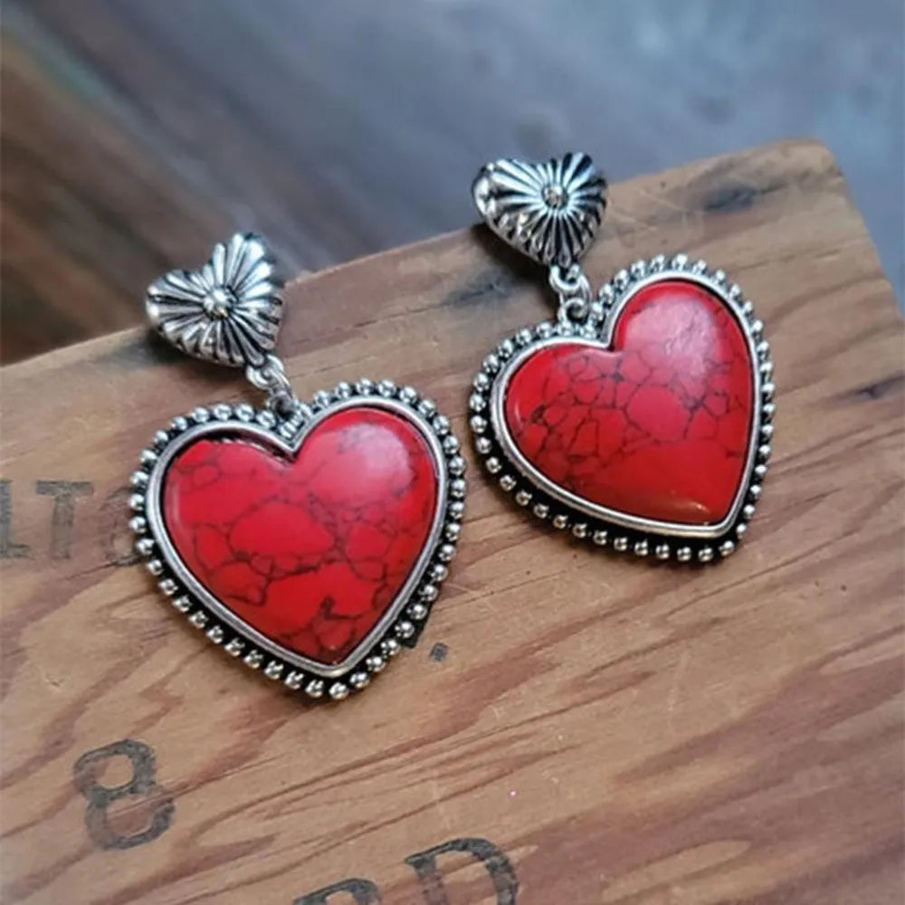 Red heart-shaped pendants with silver frames on a wooden surface